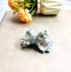 Vue detaillee d'un pince a cheveux noeud en satin bleu clair ornee de perles et de cristaux.