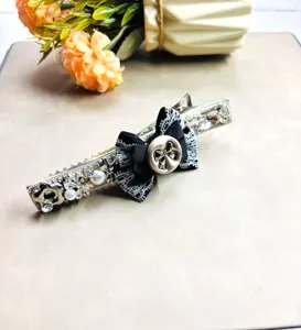 Vue detaillee de l'elegante pince a cheveux noire avec noeud en dentelle et strass.