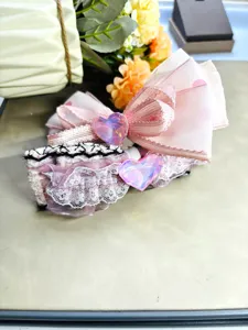 Close-up of sweet pink plush hair bow with lace trim and sparkling heart crystal charm.
