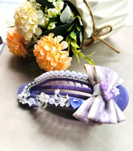 Gros plan détaillé d'une grande pince à cheveux violette décorée de perles et strass.