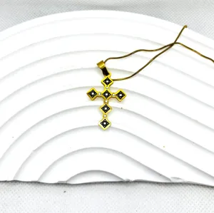 Gros plan d'un élégant pendentif croix dorée avec incrustation noire et chaîne assortie.