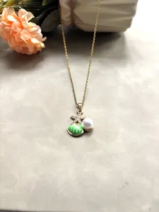 Gros-plan du détail de collier perle coquillage étoile de mer dorée, zircon et émail.