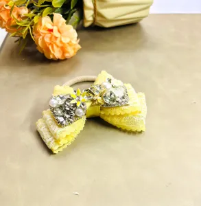 Détail d'un élastique nœud jaune étincelant avec des strass, des perles et de la dentelle.