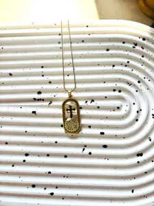 Vue détaillée du collier pendentif croix en acier titane plaqué or avec strass.