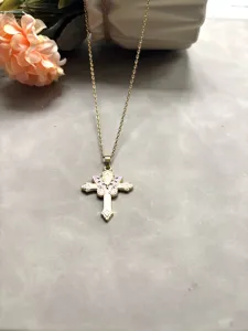 Gros plan détaillé d'un collier croix doré chic avec un joli pendentif papillon rose.