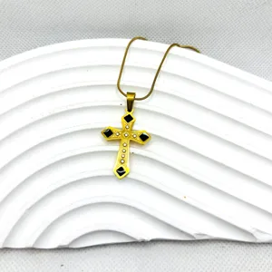 Collier pendentif croix en acier titane doré avec strass noirs style hip-hop chic.