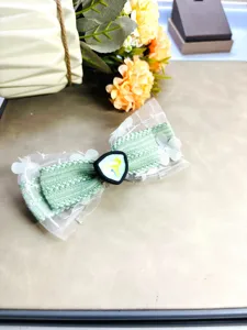 Détail de pince à cheveux nœud en dentelle verte, accessoire de coiffure style doux.