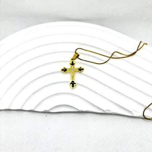 Vue détaillée du collier pendentif croix doré avec émail noir et chaîne fine élégante.