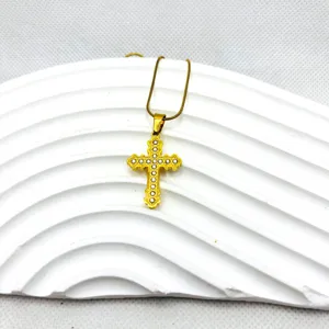 Gros plan sur le collier pendentif croix doré avec des strass étincelants, détail gothique.