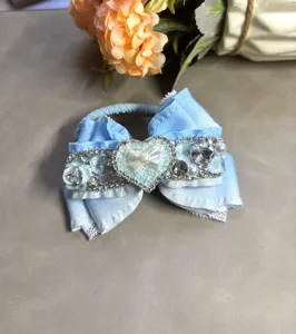 Gros plan détaillé du joli chouchou nœud bleu clair avec strass, dentelle et perles.