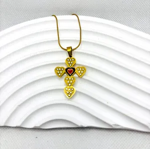 Gros plan du collier pendentif croix en acier titane doré avec des motifs de cœur.