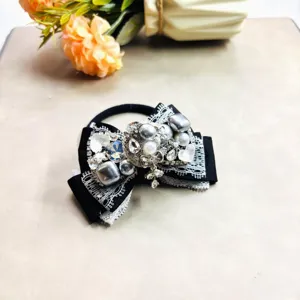 Élégant chouchou à nœud noir avec strass scintillants et perles, accessoire chic pour femmes.