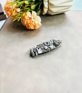 Gros plan d'une pince à cheveux vintage en argent, strass et perle, accessoire élégant.