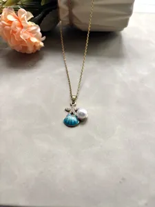 Collier en acier inoxydable doré avec pendentif étoile de mer en cristal, coquillage et perle.