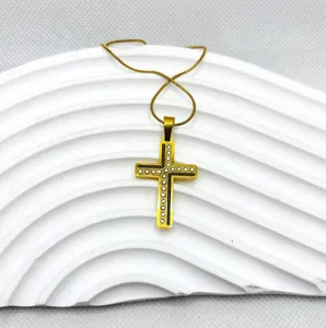 Vue détaillée du collier pendentif croix en acier titane doré avec des strass étincelants.