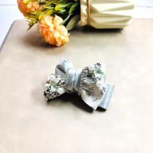Élégante pince à cheveux nœud avec strass étincellants, perles nacrées et tissu délicat.