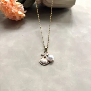 Collier en acier titane doré avec pendentif étoile de mer, coquillage et perle.