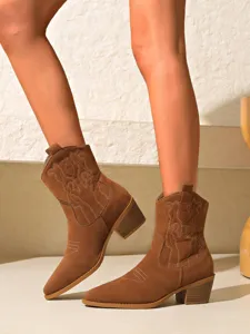 Detailed view of brown suede western cowboy boots featuring retro embroidery and chunky heel.