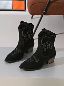 Detail view of black western cowboy boots featuring vintage embroidery and chunky block heel.