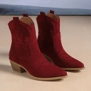 Details of red suede western cowboy boots with vintage embroidery and chunky heel design.