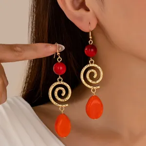 Detailed close-up view of vintage long earrings with red beads and golden spiral pendants.
