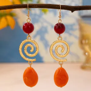 French vintage style long swirl pendant earrings with red beads and orange teardrop stones.