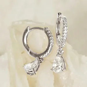 Close-up detail of silver paved hoop drop earrings featuring sparkling pear-shaped crystal stones.