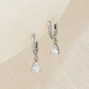 Elegant silver pavé huggie hoop earrings with dangling pear-cut cubic zirconia stones for women.