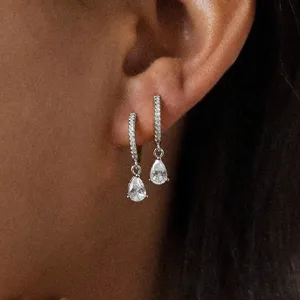 Close-up detail of stylish pave hoop earrings with sparkling pear-shaped drop stones.