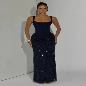Vue de détail élégante du haut corset bleu foncé et de la longue jupe à sequins scintillants.