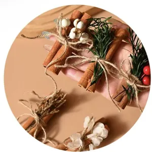 Close-up of dried cinnamon stick bouquet with red berries and twine for gift decoration.