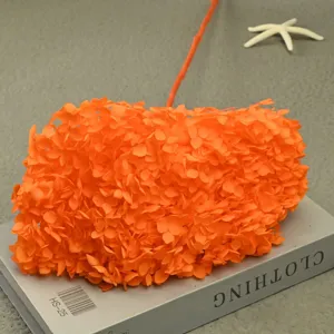 Detailed close-up view of single orange preserved hydrangea flower on gray decorative book.