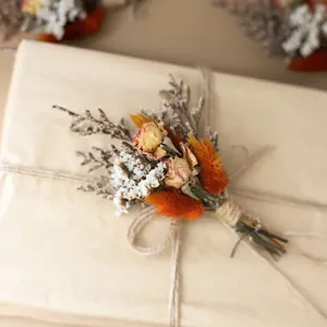 Closeup of mini dried flower bouquet with roses and bunny tails for gift box decoration.