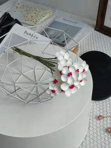 Primo piano dettagliato di composizione di fiori artificiali in cesto metallico bianco.