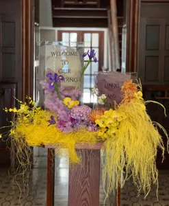 Wedding floral decor scene with clear acrylic boxes, colorful flowers and yellow sisal filler.