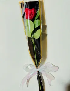 Einzelner künstlicher Rosenstrauch Detail, schwarz-goldenes Geschenkpapier mit Schleife.