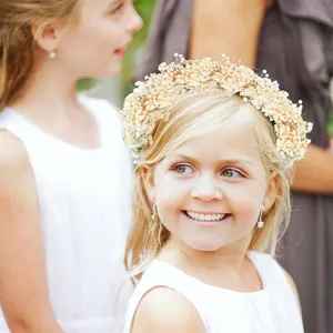 Close-up detail shot of child wearing natural preserved gypsophila flower crown for wedding.