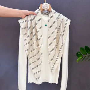 Elegant striped triangular scarf layered with a white knit top, chic women fashion accessory.