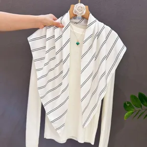 Detailed view of a fashionable black and white striped triangular scarf styled with knitwear.