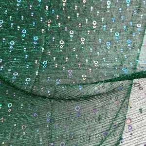 Close-up detail of dark green sequin sheer gauze fabric showcasing iridescent circles pattern.