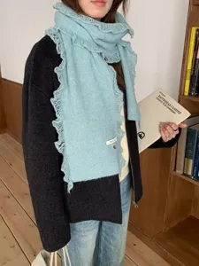 Cozy light blue knitted scarf with delicate lace frayed edges. Detailed view of winter warm neckwear.