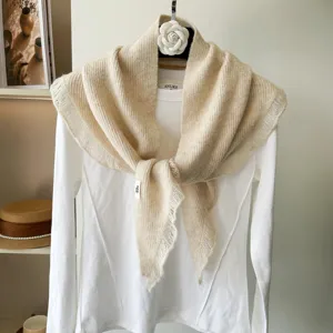 Detailed view of beige ribbed knit triangle scarf and shawl, soft texture, elegant drapery.