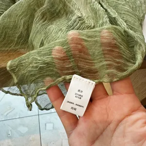 Solid color crinkled breathable scarf detail showcasing lightweight fabric texture and label.