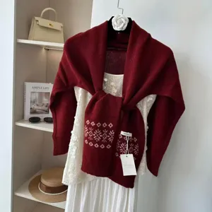 Detailed view of burgundy knit jacquard shawl layered over white sequin top with wool tag.