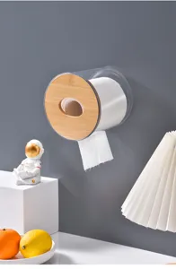 Close-up of a clear cylindrical wall-mounted tissue holder featuring a wooden lid in room scene.