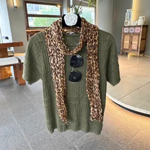 Green knitted short sleeve top paired with a chic leopard print scarf and stylish sunglasses.