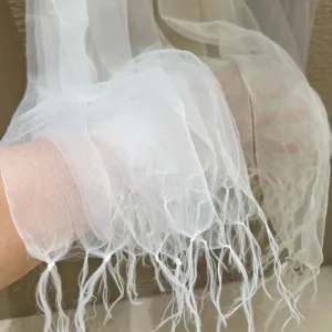 Detail shot of lightweight sheer mesh tassel scarf, ethereal spring summer accessory.