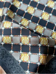 Silk square scarf detail featuring a classic chain and geometric pattern, elegant accessory.