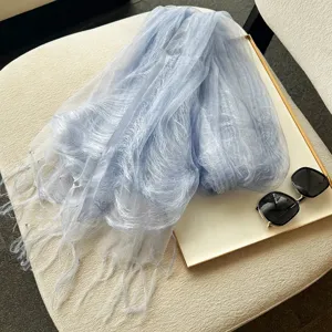 Detailaufnahme des hellblauen, strukturierten Seidenschals mit zarten Fransen und leichtem Stoff.