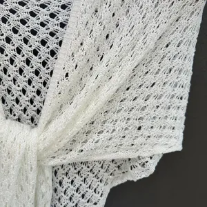 Close up of white sequin knit shawl detail, lightweight mesh scarf fabric texture view.